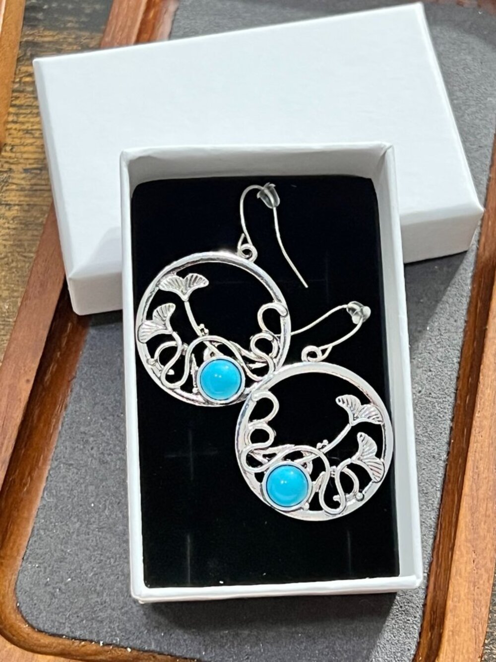 Beautiful silver-tone round dangle earrings featuring an openwork floral/leaf de